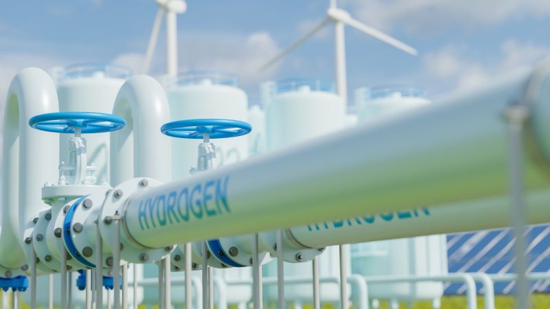 Das Bild zeigt eine erstellte Grafik mit oberirdischen Wasserstoff-Leitungen. Im Hintergrund sind Windkraftanlagen und Solaranlagen zu erkennen.