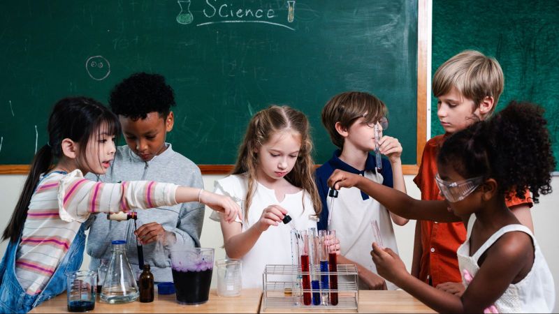 Das Bild zeigt eine Gruppe von Kindern in einer schulischen Expertimentier-Situation im wissenschaftlichen Sinne.