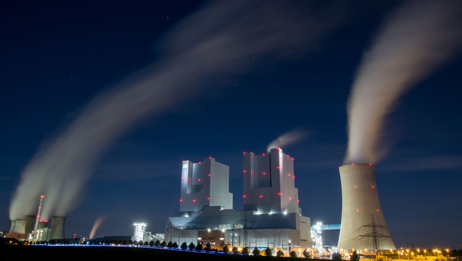 Das Bild zeigt ein Kohlekraftwerk bei nach, aus dessen Schornsteinen Rauch in dicken Schwaden zieht. 