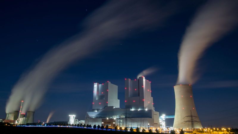 Das Bild zeigt ein Kohlekraftwerk bei nach, aus dessen Schornsteinen Rauch in dicken Schwaden zieht. 