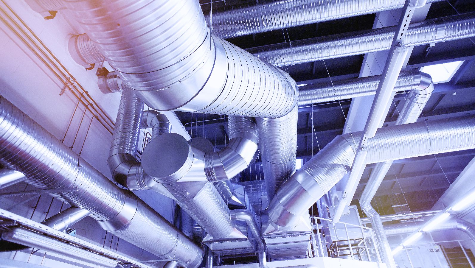 Das Foto zeigt Rohre industrieller Kälte und Wärmeversorgung an einer Decke. 