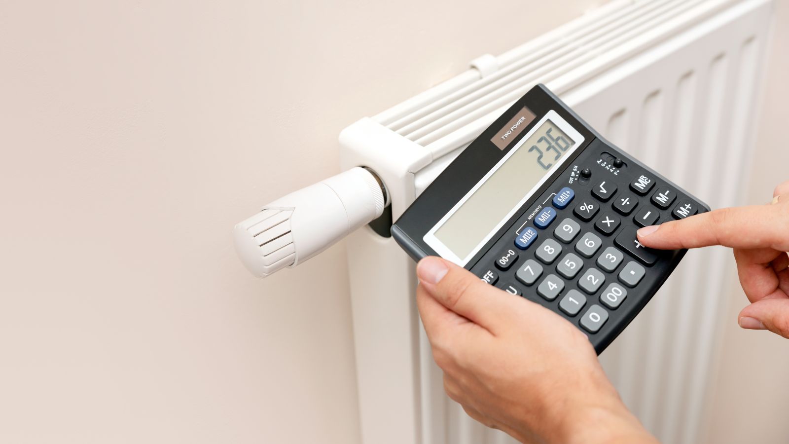 Das Bild zeigt eine Heizung als Symbol für Wärme in Gebäuden und zwei Hände mit Taschenrechner, was die Kalkulation der Heizkosten veranschaulicht.