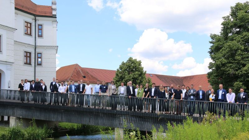 Das Bild zeigt eine Gruppenaufnahme der Teilnehmenden auf einer Brücke vor einem Schloss stehend.