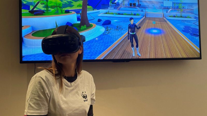 Das Bild zeigt eine junge Frau, die eine VR-Brille trägt und sich in der 