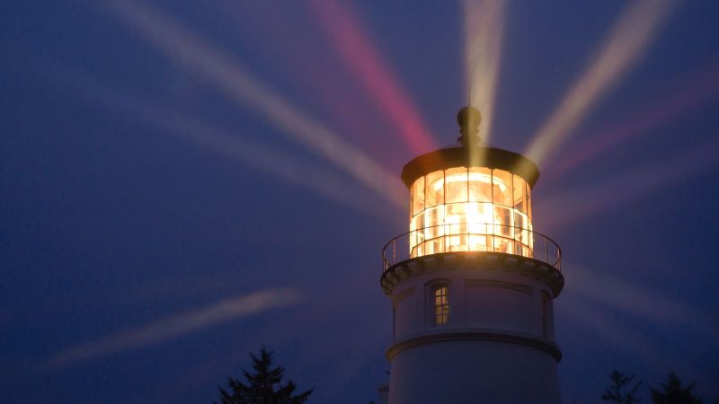 Das Bild zeigt eine Leuchtturmspitze in der Dunkelheit.