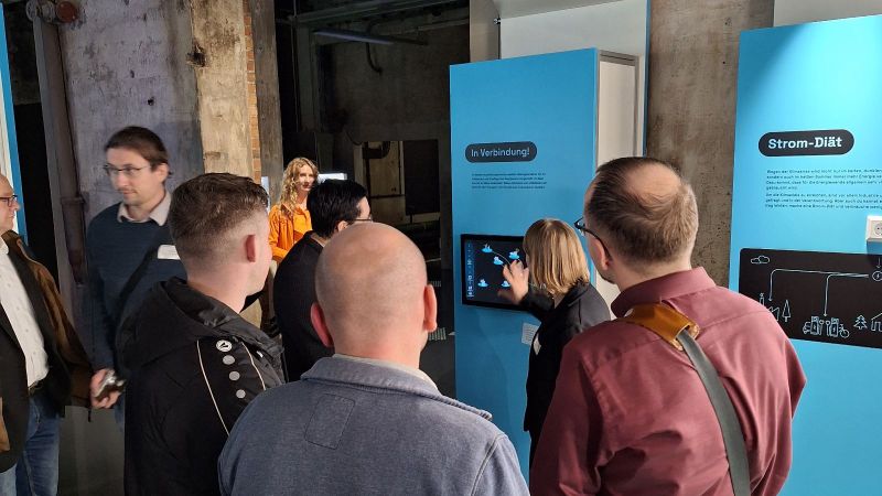 Das Bild zeigt mehrere Menschen vor einem blauen Modul der Ausstellung 