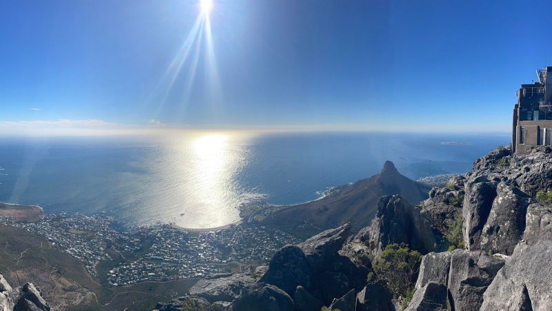 Das Bild zeigt einen Panoramablick vom Tafelberg in Kapstadt auf Camps Bay und den Lion’s Head auf der rechten Seite. 