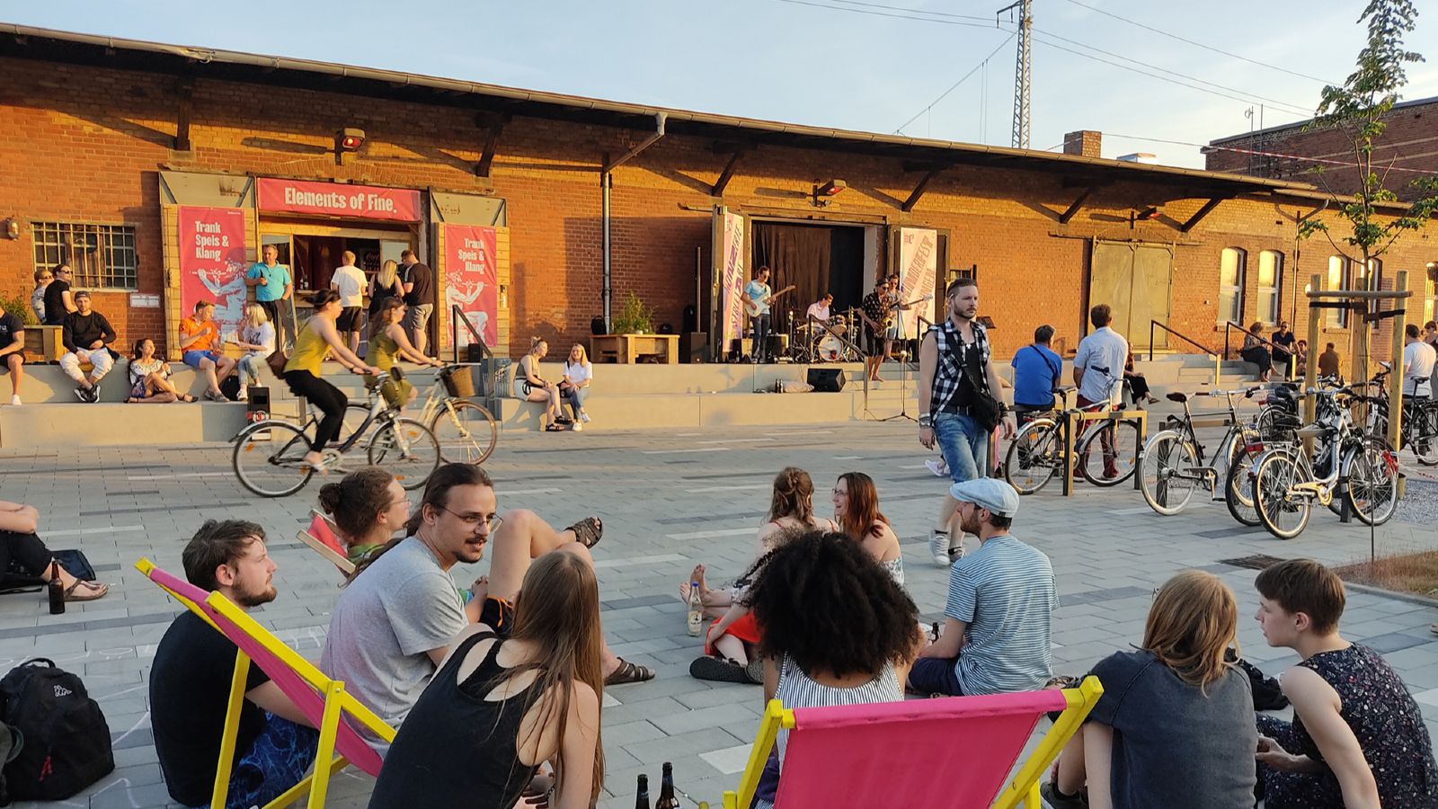 Das Bild zeigt Menschen, die vor dem Bunten Bahnhof in Cottbus sitzen