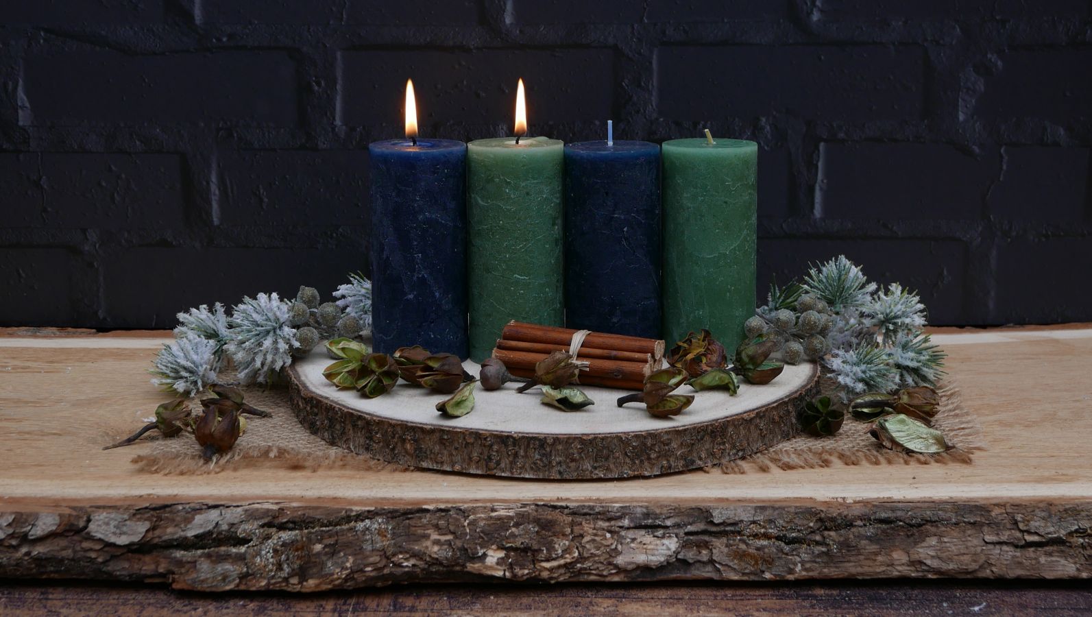 Zu sehen ist ein Adventsgesteck in der Farbwelt Brau-Türkis mit vier Kerzen, von denen zwei brennen.