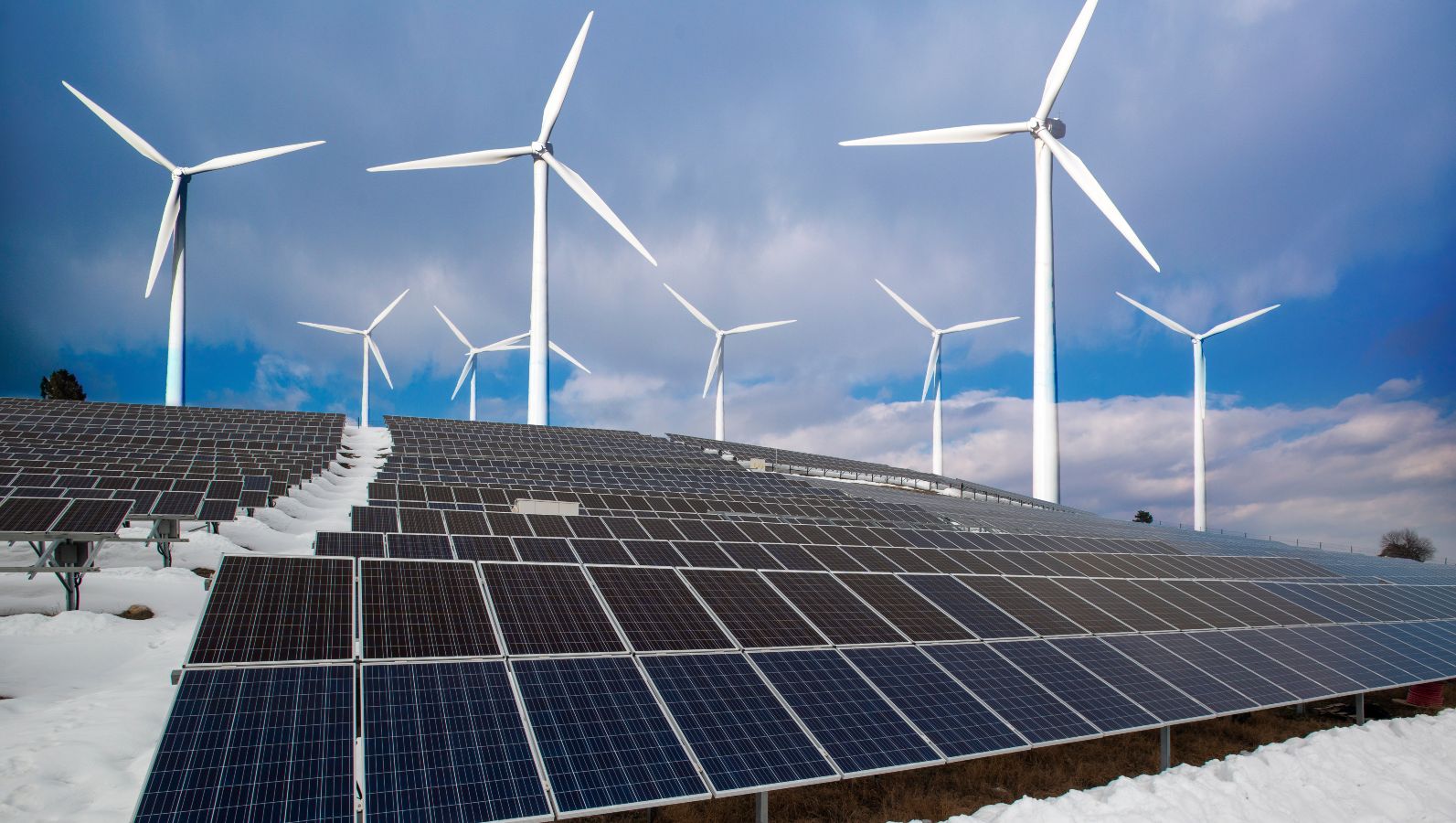 Das Bild zeigt Windräder und Solarpanels in einer winterlichen Landschaft.