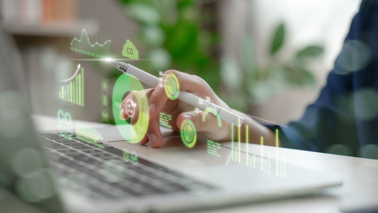 Das Bild zeigt eine Hand, die einen Stift hält. Vor einem Laptop sieht man ein Dashboard mit Analysedaten und Kennzahlen.