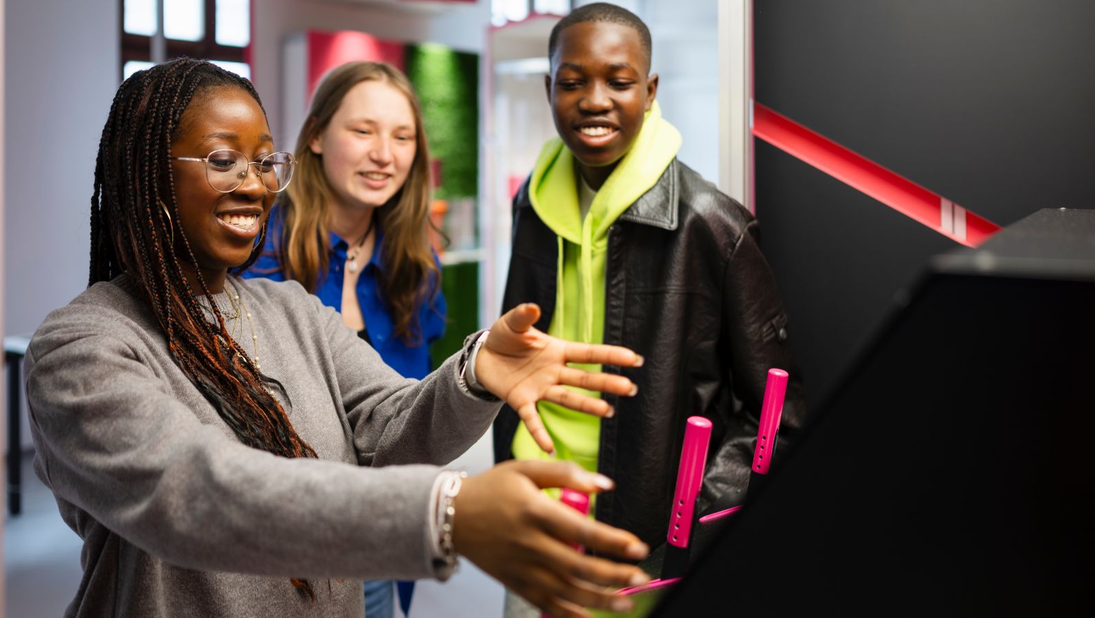 The image shows several young people enthusiastically exploring an interactive exhibit at the Power2Change exhibition.